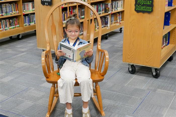 Female student sitting on a chair reading in a library